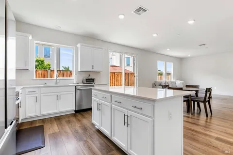 a kitchen with white cabinets and wooden floor