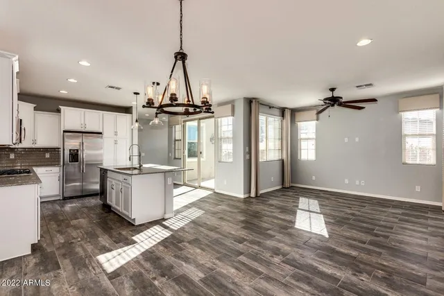 a view of a kitchen with kitchen island wooden floors appliances and windows