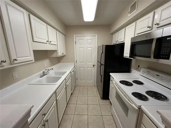 a kitchen that has a sink a microwave and refrigerator