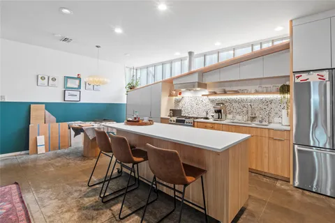 a kitchen with stainless steel appliances kitchen island a table chairs in it and wooden floors