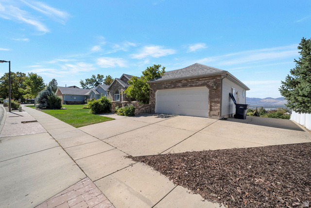 11922 Bluff View Drive Sandy, UT 84092 - Photo 3 of 30 View of side of property featuring brick siding, concrete driveway, a lawn, and a garage