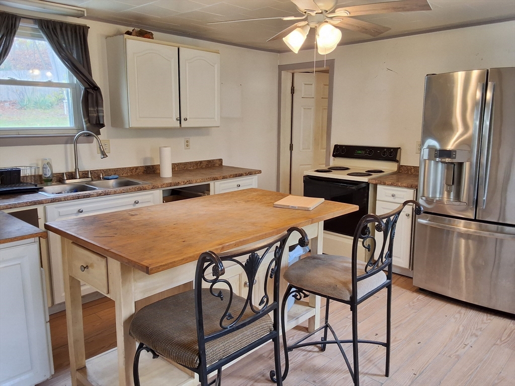 72 Maple Street Warren, MA 01083 - Photo 7 of 16 a kitchen with stainless steel appliances a table chairs and a refrigerator