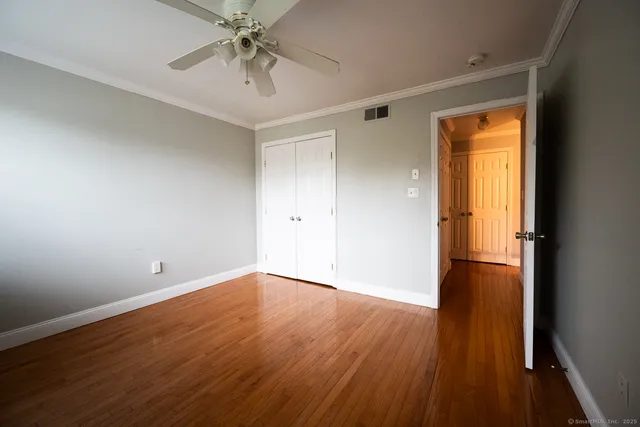 a view of empty room with wooden floor and fan