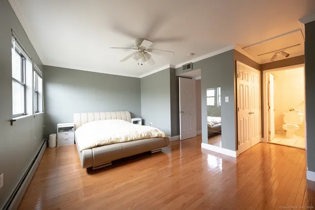 a spacious bedroom with a bed and wooden floor