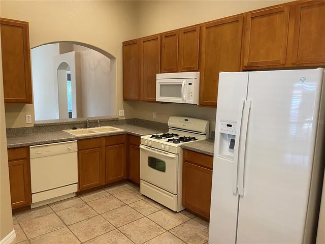 a kitchen with granite countertop a refrigerator and a stove top oven