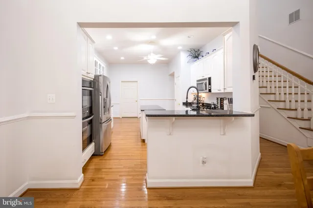 a large kitchen with stainless steel appliances granite countertop a stove top oven a refrigerator a sink and dishwasher with wooden floor