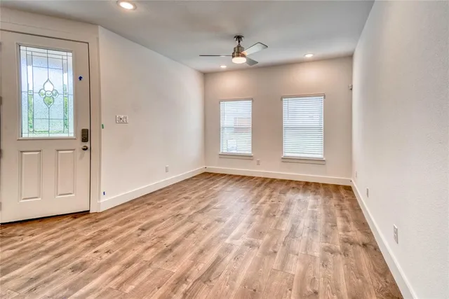 a view of an empty room with wooden floor and window