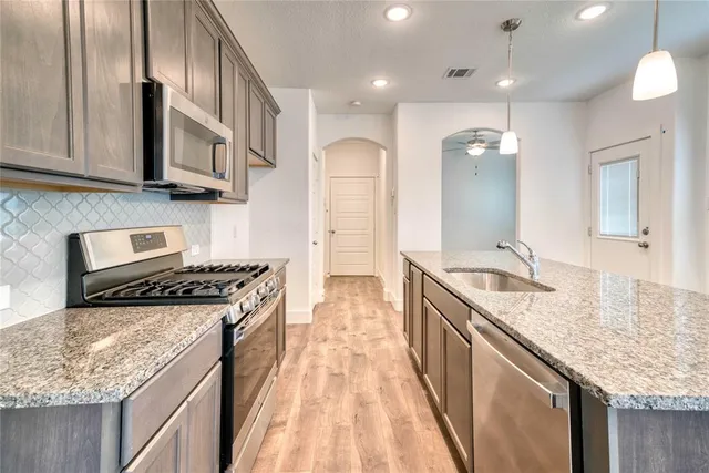 a kitchen with stainless steel appliances granite countertop a sink stove and refrigerator