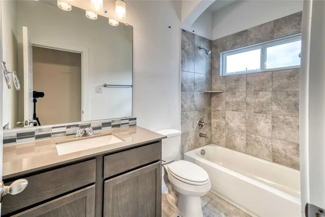 a bathroom with a granite countertop sink toilet mirror and bathtub