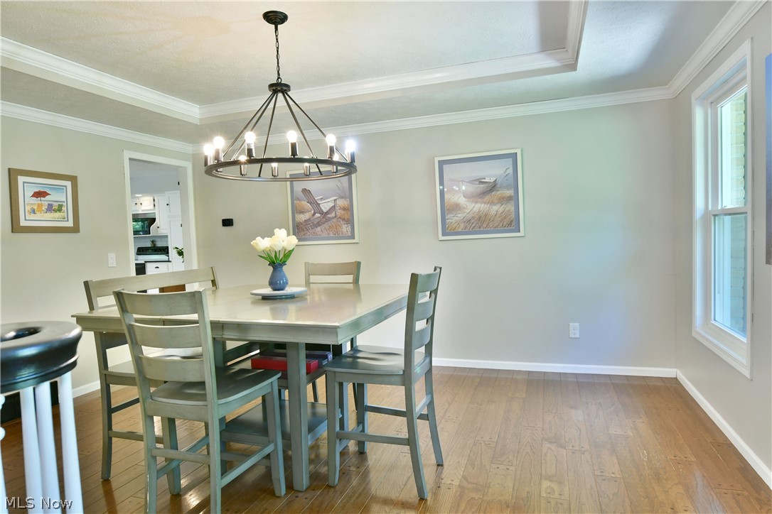 13491 Woodin Road Chardon, OH 44024 - Photo 11 of 35 Dining space featuring an inviting chandelier, ornamental molding, hardwood / wood-style flooring, and a tray ceiling