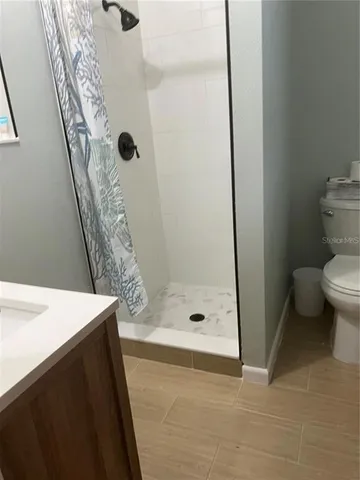 a bathroom with a granite countertop sink a toilet and shower