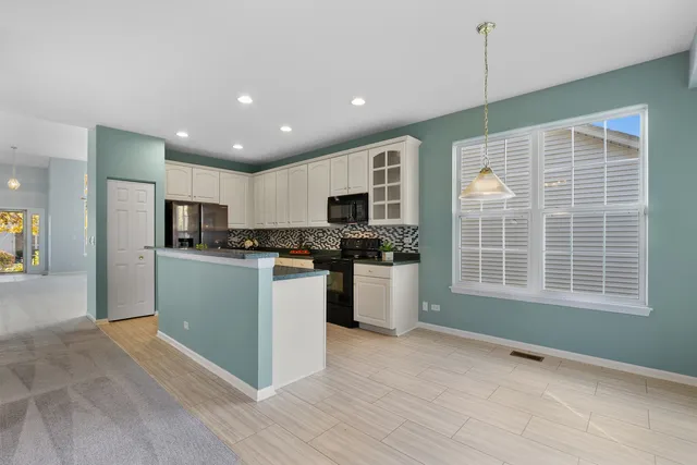 a kitchen with stainless steel appliances granite countertop a refrigerator oven a sink dishwasher with a dining table and chairs