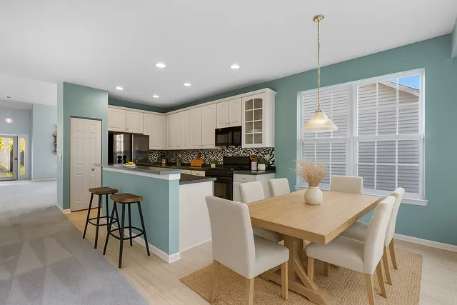 a kitchen with stainless steel appliances granite countertop a stove a refrigerator a kitchen island a dining table and chairs