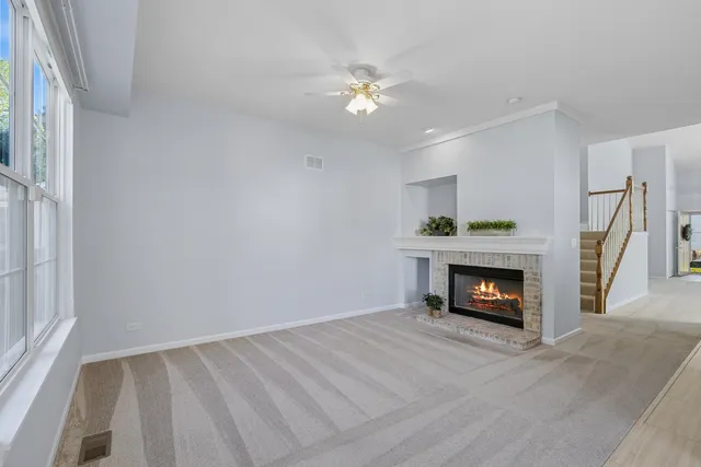 a view of an empty room with wooden floor fireplace and a window