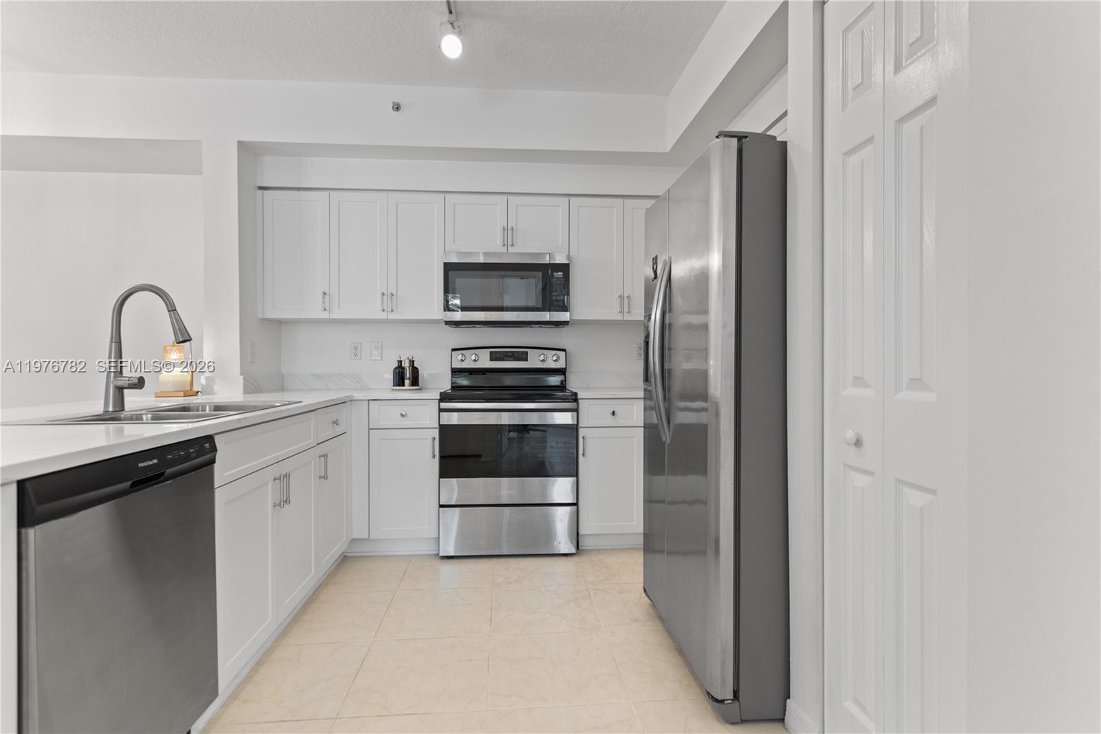 6851 Southwest 44th Street, Unit 107 Miami, FL 33155 - Photo 14 of 41 a kitchen with stainless steel appliances a refrigerator sink and white cabinets