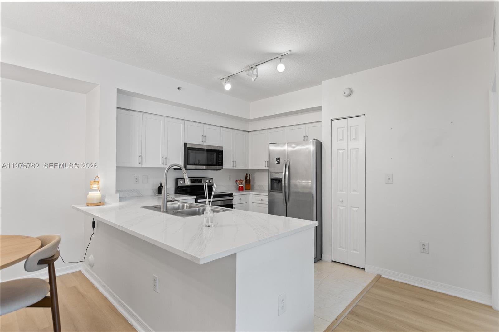 6851 Southwest 44th Street, Unit 107 Miami, FL 33155 - Photo 30 of 41 a kitchen with stainless steel appliances a refrigerator oven a sink dishwasher and white cabinets with wooden floor