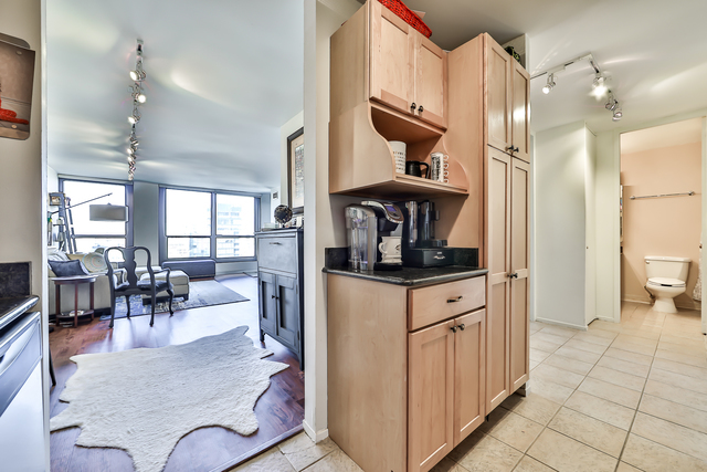 1030 North State Street, Unit 20D Chicago, IL 60610 - Photo 10 of 22 a kitchen with stainless steel appliances kitchen island granite countertop a refrigerator a stove a dining table and chairs with wooden floor