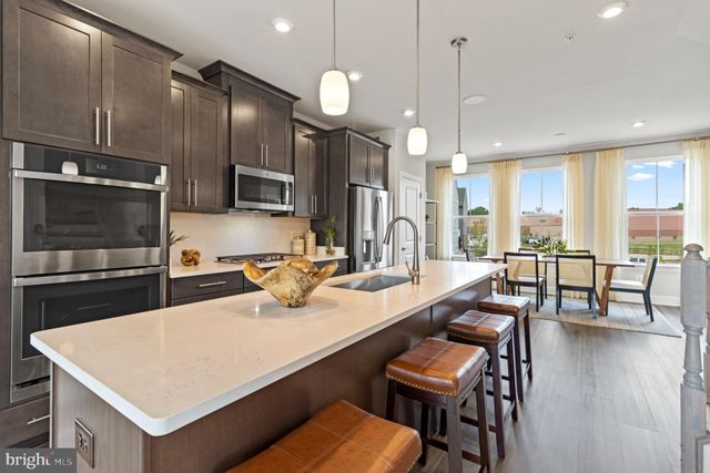a kitchen with a dining table chairs sink and wooden floor