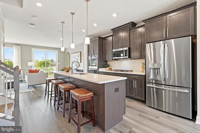 a kitchen with stainless steel appliances granite countertop a refrigerator a stove a sink a dining table and chairs with wooden floor