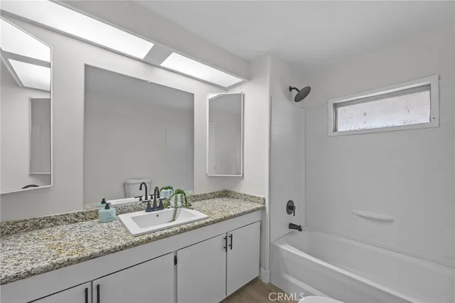 a bathroom with a granite countertop sink and mirror with bathtub