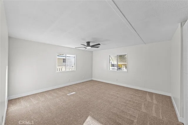an empty room with windows and ceiling fan