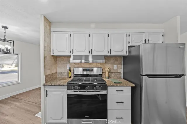 a kitchen with refrigerator a stove and white cabinets