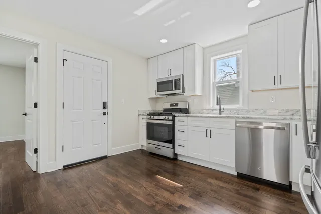 a kitchen with granite countertop white cabinets and stainless steel appliances
