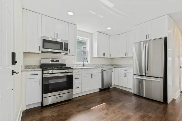 a kitchen with cabinets stainless steel appliances and wooden floor