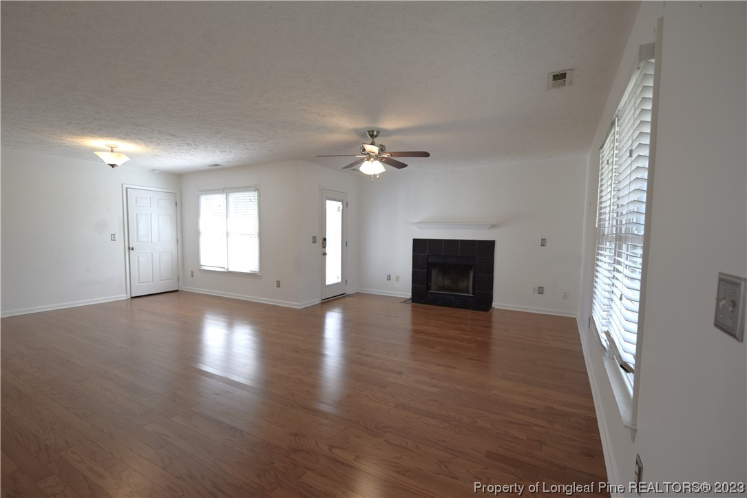 512 Kernstown Road Raeford, NC 28376 - Photo 6 of 25 an empty room with wooden floor fireplace and windows