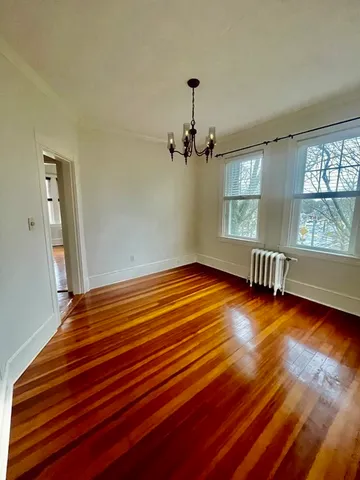 a view of empty room with a window and wooden floor