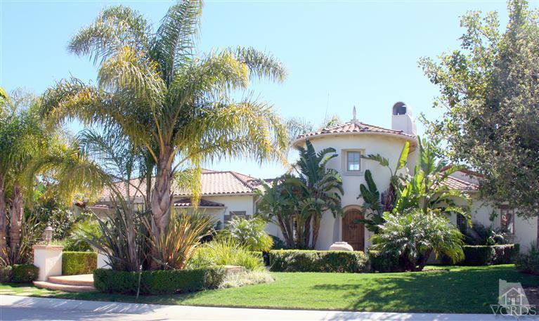a front view of a house with a yard and palm trees