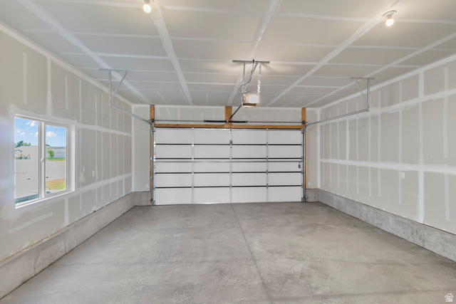 1213 West 500 South Logan, UT 84321 - Photo 24 of 29 Spacious garage featuring a concrete floor, white sectional garage door, multiple windows, exposed wood framing, and overhead lighting