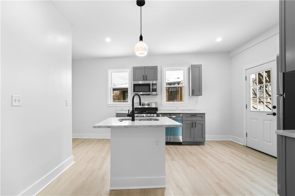 309 North Mathilda Street Pittsburgh, PA 15224 - Photo 8 of 30 a kitchen with kitchen island a stove a sink and a refrigerator