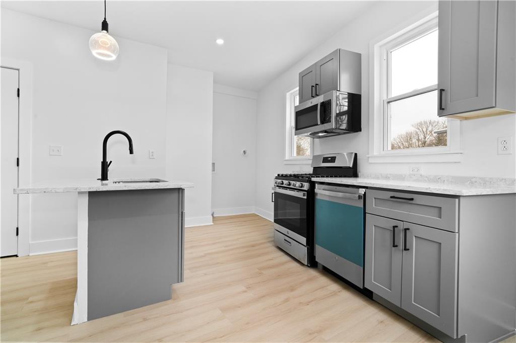 309 North Mathilda Street Pittsburgh, PA 15224 - Photo 10 of 30 a kitchen with stainless steel appliances granite countertop a sink and a stove top oven with wooden floor