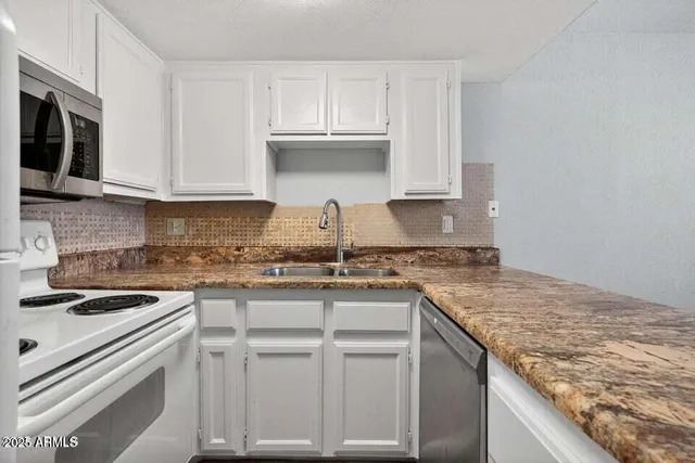 a kitchen with granite countertop a sink stove and cabinets