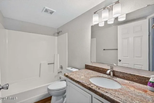 a bathroom with a granite countertop toilet a sink and a mirror