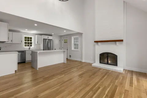 a view of a kitchen and an empty room with a fireplace