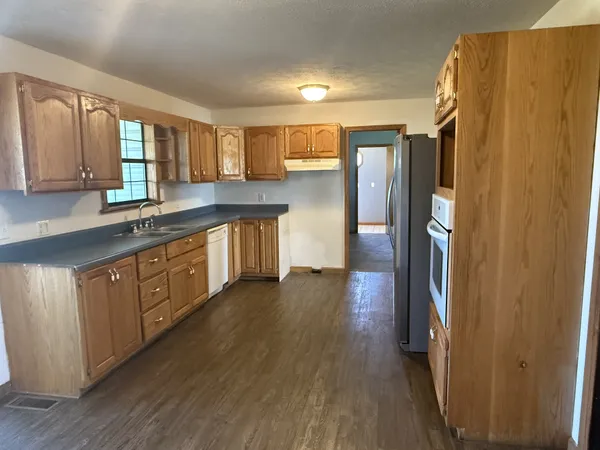 a kitchen with stainless steel appliances granite countertop a sink a stove cabinets and wooden floor