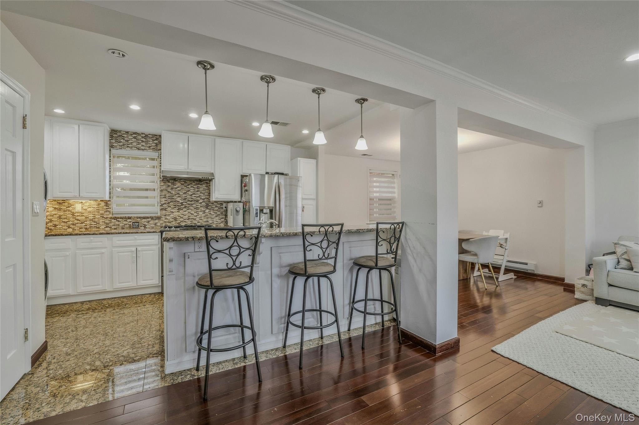 22904 67th Avenue, Unit 38 Queens, NY 11364 - Photo 3 of 17 a kitchen with stainless steel appliances kitchen island granite countertop a dining table chairs and sink