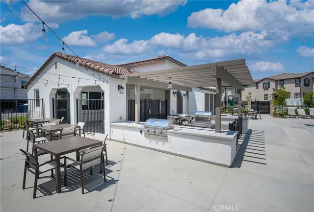 a view of a patio with dining table and chairs with a barbeque