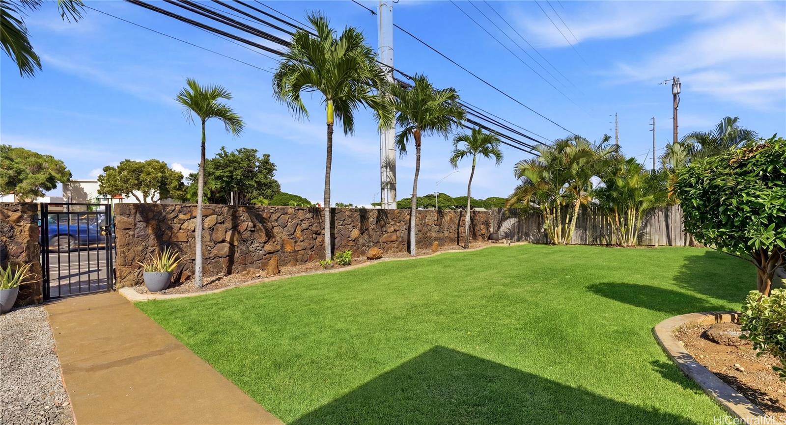91-779 Fort Weaver Road Ewa Beach, HI 96706 - Photo 20 of 25 Securely walled and gated level yard featuring tropical palm trees and lush landscaping.