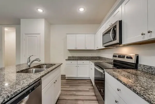 a kitchen with granite countertop cabinets stainless steel appliances and a sink