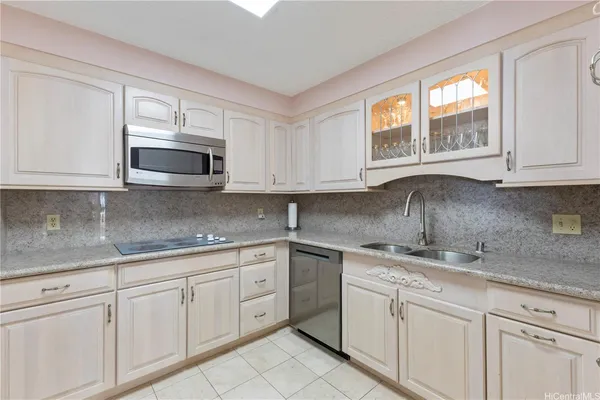 a kitchen with white cabinets appliances a sink and a window