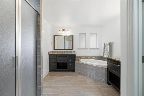 a spacious bathroom with a bathtub sink and mirror
