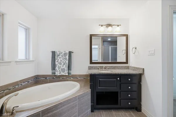 a bathroom with a tub sink and mirror