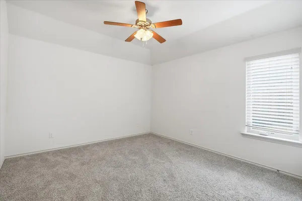 an empty room with a window and a ceiling fan