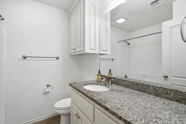 a bathroom with a granite countertop sink and a toilet