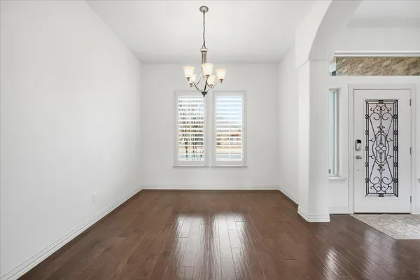 an empty room with wooden floor windows and entrance