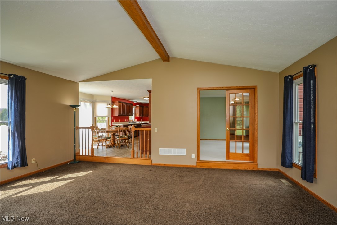 12565 Alpha Road Hiram, OH 44234 - Photo 9 of 50 Unfurnished living room with baseboards, visible vents, vaulted ceiling with beams, and carpet