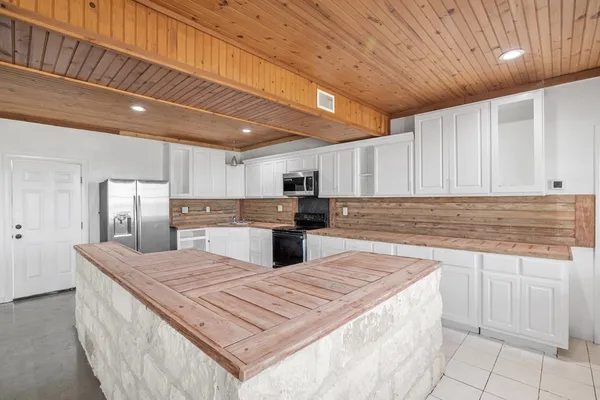 a large kitchen with kitchen island a sink a counter space stainless steel appliances cabinets and a counter top space